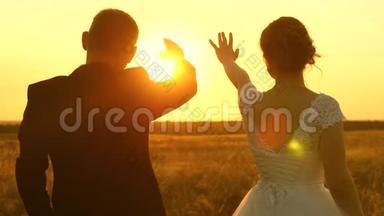 一男一女在夕阳下用手<strong>秀出</strong>一颗心。浪漫之旅中的恋人。团队合作